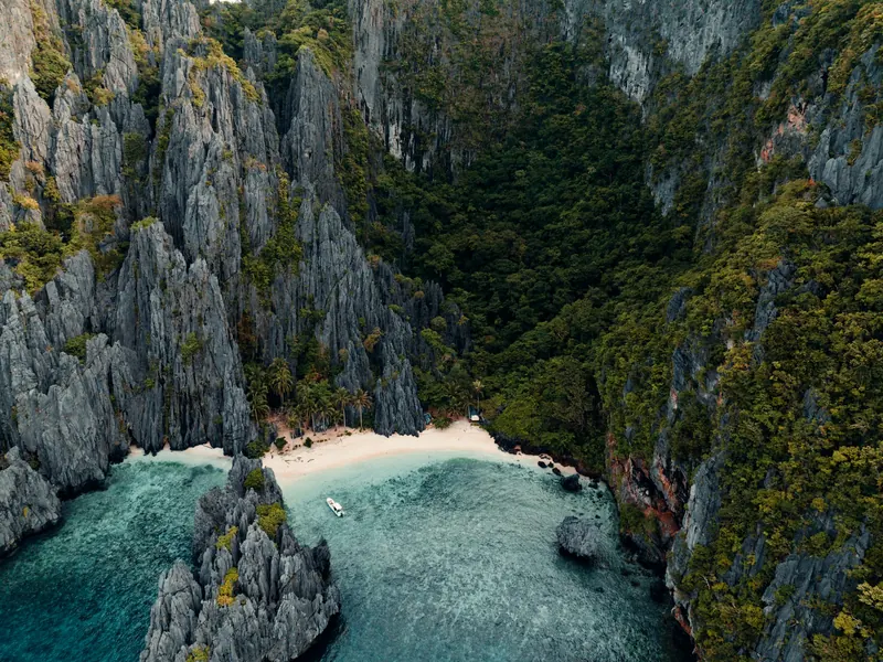Ukryta zatoka z wapiennymi klifami i łodzią bangka, El Nido, Filipiny