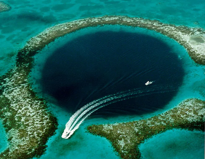 Great Blue Hole z lotu ptaka: ciemnogranatowy okrągły otwór wśród turkusowej rafy, łódź na powierzchni - zdjęcie poglądowe